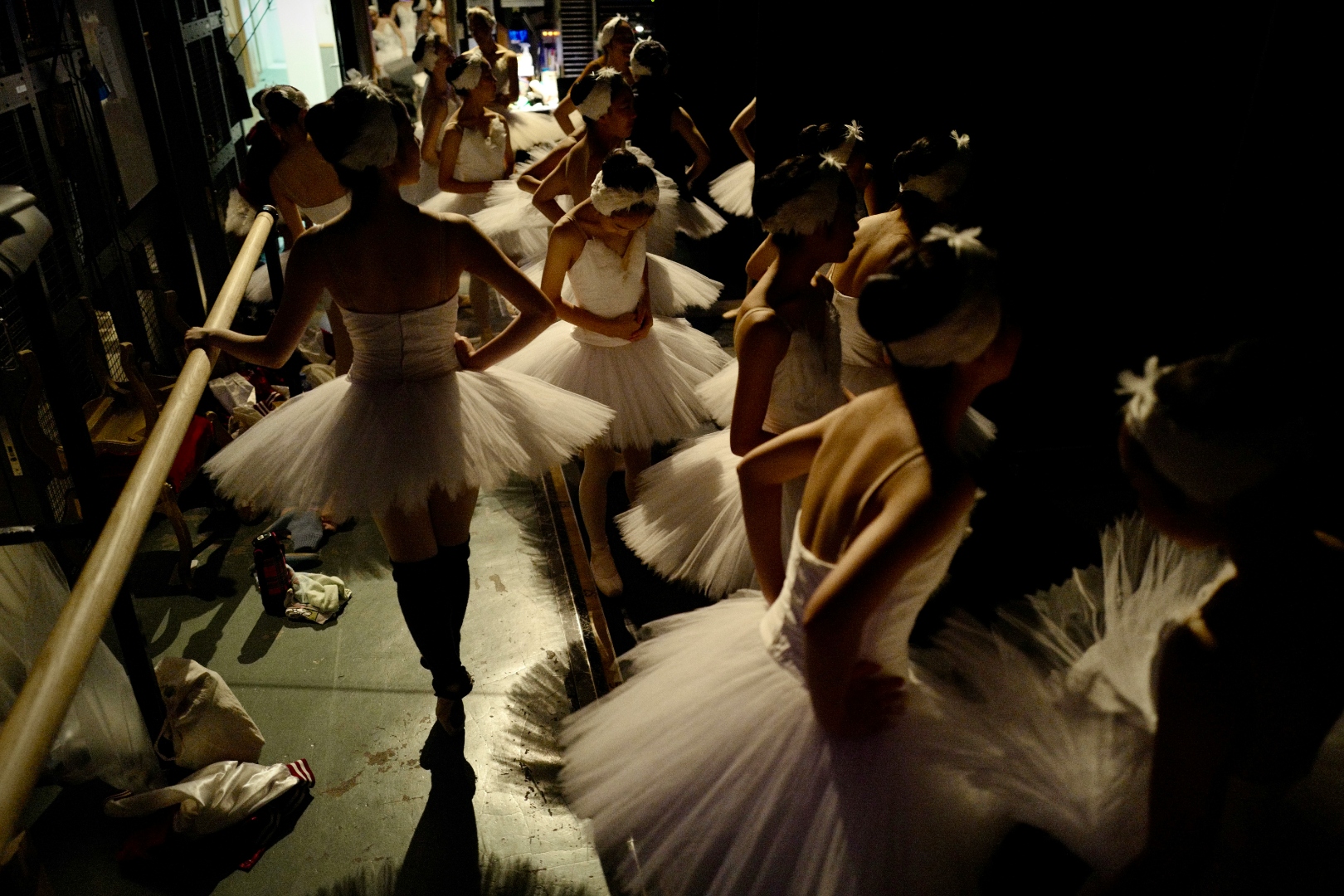 Adult ballet dancers in white tutus gathered backstage